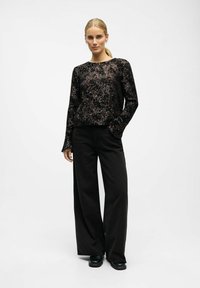 Black sequined long-sleeve top paired with wide-leg black pants. The top features a round neckline and subtle shimmer texture.