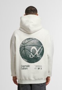 Felpa grigia chiara con una grande grafica verde di un pallone da basket sul retro, che presenta il testo "Courtside Culture." Materiale in cotone con una texture morbida.