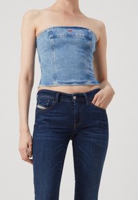 Ljusblå denim crop top utan axelband med strukturerade sömmar och en framficka. Kombinerad med mörkblå skinny jeans med stickningsdetaljer.