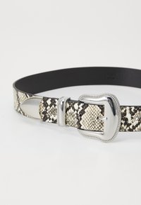 Ceinture noire étroite avec un motif en peau de serpent crème et noir, dotée d'une boucle en argent et d'accents métalliques décoratifs. Doublure en cuir lisse.