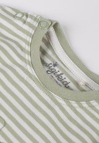 Grün-weiß gestreiftes Baumwollhemd mit rundem Halsausschnitt, Druckknöpfen an der Schulter und leichtem Stoff. Etikett innen sichtbar.