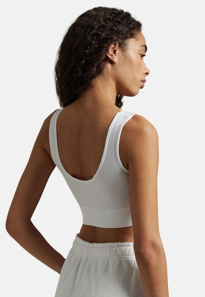 Bílý žebrovaný crop top s širokými ramínky, kulatým výstřihem a přiléhavým střihem. Jemná textura s hladkým povrchem a minimem švů.