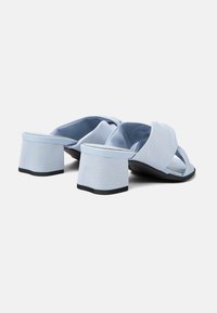 Le ciabatte in tessuto blu presentano un design a fascia incrociata, un tacco spesso e squadrato con un accento nero e una morbida fodera interna.
