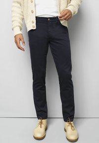 Pantalons navy à coupe slim et tissu lisse, dotés d'une fermeture à bouton à l'avant, de poches latérales et de détails de coutures visibles.