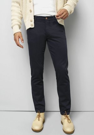 Marineblaue Hose mit schmaler Passform und glattem Stoff, ausgestattet mit einem Knopfverschluss vorn, Seitentaschen und sichtbaren Nähdetails.