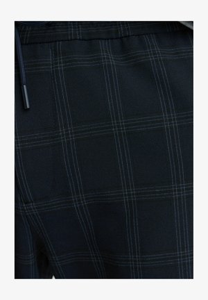 Granatowy materiał z subtelnym wzorem w kratę i jasnoniebieskimi liniami. Materiał wydaje się miękki o gładkiej fakturze. Zawiera detal ze sznurkiem.