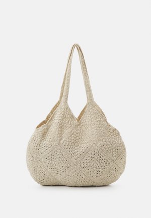 Sac à bandoulière beige en crochet avec un fond arrondi et deux longues anses, présentant un motif en losanges réalisé avec des sections carrées en crochet.