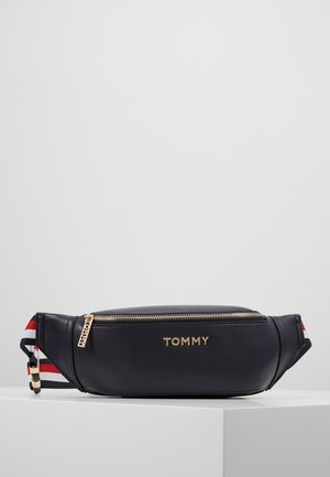 Czarna skórzana nerka z złotym suwakiem i logo "TOMMY", wyposażona w regulowany pasek w czerwono-biało-niebieskie paski.