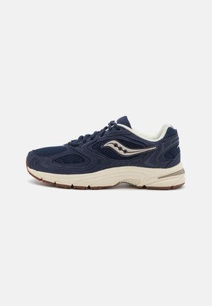 Scarpe da ginnastica blu navy con tomaia in rete, suola intermedia color crema e suola in gomma marrone. Presentano un logo argentato e dettagli texturizzati sui lati.