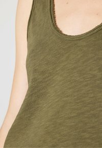 Olive green tank top made of soft fabric, featuring a scoop neckline with raw edges, and a relaxed fit that drapes gently.