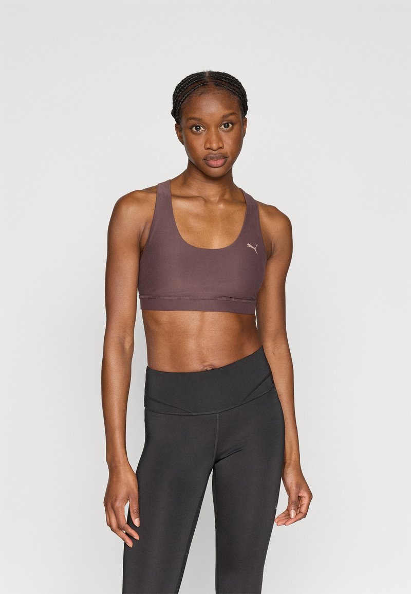 Καφέ αθλητικό μπουστάκι από ελαστικό ύφασμα με στρογγυλή λαιμόκοψη και φαρδιές τιράντες, με διακριτικό λογότυπο στην αριστερή πλευρά. Συνδυάζεται με μαύρο κολάν.