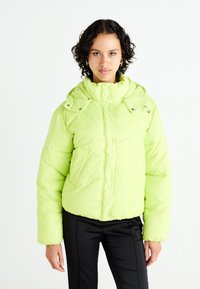 Lime green puffer jacket with a high collar, snap closure, and oversized fit. Features a smooth, shiny texture and two side pockets.