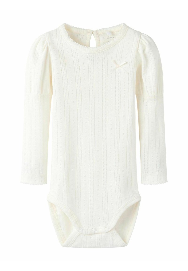 Biały, długi rękaw bodysuit z prążkowanej tkaniny, z falbaniastymi mankietami i małą wstążką jako akcentem. Zapięcie na plecach w formie otworu kluczowego z zatrzaskami na dole.