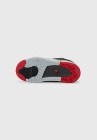 Semelle de sneaker noire et grise avec des accents rouges et des motifs texturés. Présente un logo Jumpman noir proéminent sur un fond gris.
