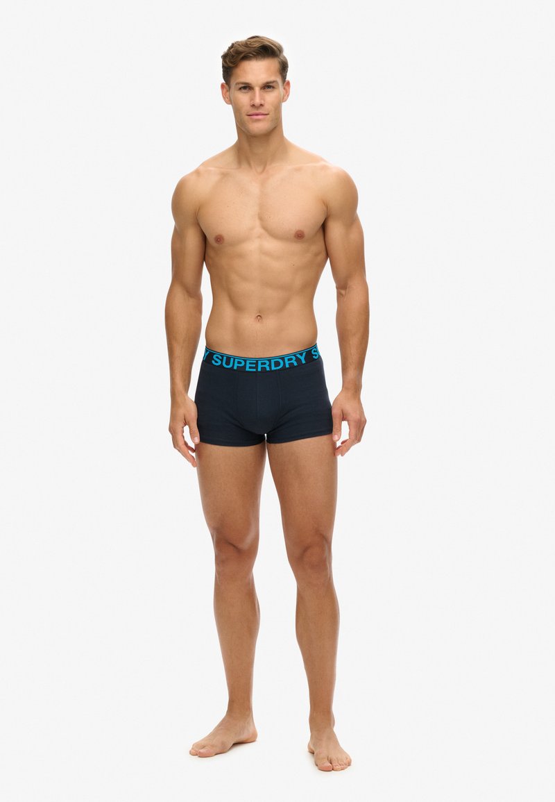 Bóxers negros con una cinturilla turquesa de "Superdry", hechos de una tela suave, que cuentan con un diseño ajustado y una longitud hasta medio muslo.