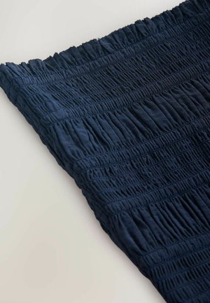 Prim-plan cu material bleumarin având un adunat elastic smock orizontal și detaliu texturat cu pliuri.