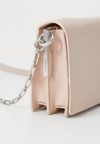 Borsa a tracolla in finta pelle rosa chiaro con dettagli in metallo argentato, dotata di una tracolla a catena e chiusura con zip.