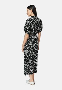Czarnobiały kwiatowy kombinezon z krótkimi rękawami, wcięciem w talii i szerokimi nogawkami. Gładki materiał i minimalistyczny design.
