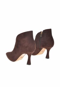 Stivali alla caviglia in suede marrone con punta affusolata, tacco a stiletto di 5 cm e zip sul retro. Il design presenta una texture liscia e accenti sottili.