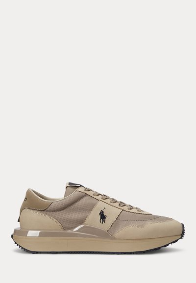 Beige low-top sneaker with lace-up front, textured fabric and leather panels, black horse logo on side, and thick rubber sole with grip tread.