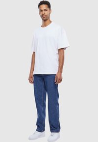 Hvit bomull crew-neck t-skjorte med korte ermer, kombinert med blå rettlegede denimjeans og hvite joggesko. Enkelt, uformelt antrekk.