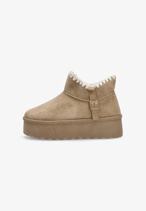 Botín de ante en tono marrón claro con suela de plataforma elevada, que presenta un forro de piel sintética y costuras en zigzag a lo largo del borde superior y una correa lateral.