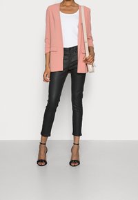 Rosa blazer, vit tanktopp, svarta läderbyxor, svarta klackar med remmar, liten axelväska; slank, skräddarsydd passform, öppen frampart.