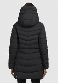 Zwarte gewatteerde winterjas met een capuchon, chevronstiksels en een middellange stijl met een gladde textuur. Ritssluitingen aan de zoom.