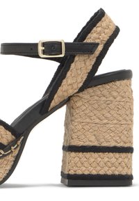 Sandale compensée avec talon et brides en corde beige tissée, bordure en cuir noir et bride de cheville avec boucle dorée.