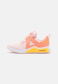Lichtroze en oranje sport sneaker met witte zool, gele luchtkussen, vetersluiting aan de voorkant en het Nike-logo op de hiel en tong.