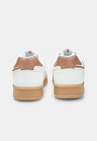 White sneakers with brown suede accents, round toe, textured rubber sole, and padded collar; minimalistic design with contrasting materials.
