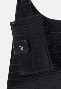 Czarna skórzana torba na ramię z teksturą krokodylej skóry i małą odpinaną kieszonką. Złote okucia przy zapięciu kieszonki.