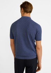 Polo bleu marine à manches courtes avec motif texturé, col et ourlet côtelés. Caractérisé par une finition lisse et un design ajusté.