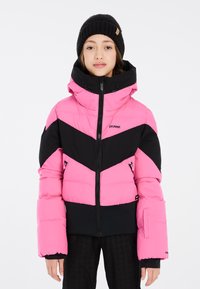 Veste rembourrée rose et noire avec un design en chevrons, col montant et fermeture éclair. Dotée de deux poches latérales et de poignets élastiques. Porté avec un bonnet noir.