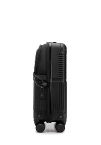 Czarna walizka z twardą skorupą, teksturowanymi bokami, czterema obrotowymi kółkami, zamkiem szyfrowym TSA i zamykaną kieszenią z przodu.
