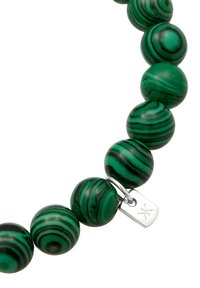 Grüne und schwarze gestreifte runde Perlen aus Malachit, mit einem metallischen Verschluss, der ein kleines Etikett trägt. Glatte Textur und polierte Oberfläche.