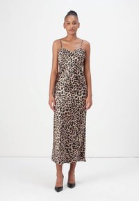 Leopard print midi dress with spaghetti straps, satin-like texture, fitted silhouette, flowing skirt, and side slit, worn with black heels.
