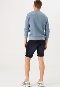 Suéter de punto acanalado de color azul claro, pantalones cortos de mezclilla oscuros y zapatillas ligeras. Incluye características como un tejido texturizado y un corte ajustado.