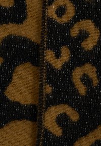 Tejido de estampado de leopardo que presenta una base marrón texturizada con manchas negras, bordes cosidos y un ligero brillo en toda su superficie.