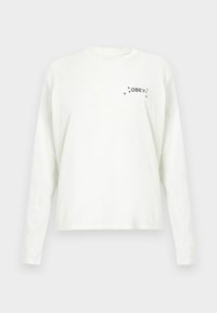 Witte katoenen T-shirt met lange mouwen, met de tekst "OBEY" en kleine steraccenten op de linkerborst voorkant.