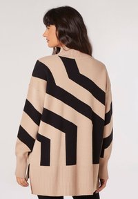 Suéter beige de gran tamaño con un audaz patrón de zigzag negro, puños y dobladillo acanalados. Material suave con aberturas laterales para mayor libertad de movimiento.