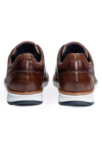 Braune Leder Schuhe mit Lochmuster, weißer Zwischensohle und Gummisohle. Runde Form mit glatter Textur und kontrastierenden dunklen Akzenten.