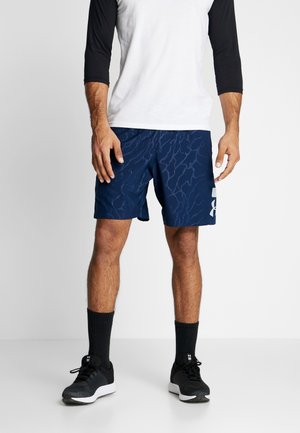 Mørkeblå træningsshorts med et diskret bølgemønster, parret med en hvid og sort t-shirt med trekvartærmer og sorte sneakers.