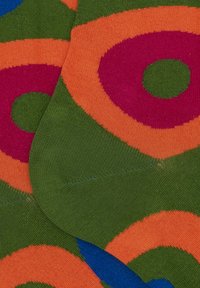 Calzini colorati con audaci motivi circolari in verde, arancione, rosa e blu, realizzati in un morbido tessuto a maglia con una superficie liscia.