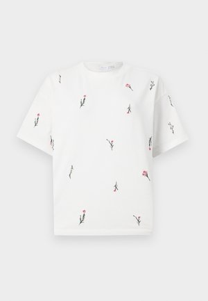 T-shirt blanc à manches courtes avec de petites broderies florales roses et vertes dispersées sur le devant, le dos et les manches.