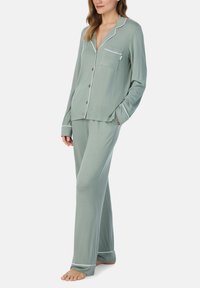 Lichtgroene pyjama set van zacht stof, met een kledingstuk met knopen aan de voorkant en een borstzakje, afgewerkt met witte bies, gecombineerd met losse broek.