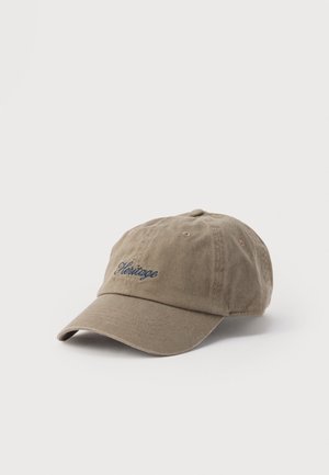 Brown baseball cap with curved visor and the word "Heritage" embroidered in dark blue on the front center.