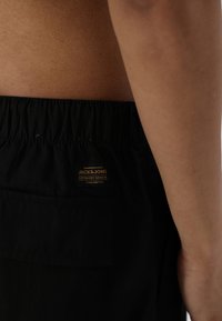 Sorte bomulds-shorts med elastisk talje og en baglomme, mærket med et lille guld "Jack & Jones"-skilt.