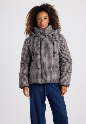 Pufferjack in een bruine geruite print, met een hoge kraag, trekkoordcapuchon en gestikte secties. Gecombineerd met een losse blauwe jeans.