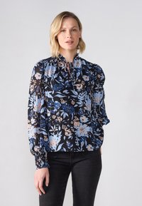 Floral blouse in navy with light blue and peach flowers. Features a gathered neckline, long puff sleeves, and elasticized cuffs. Soft fabric.